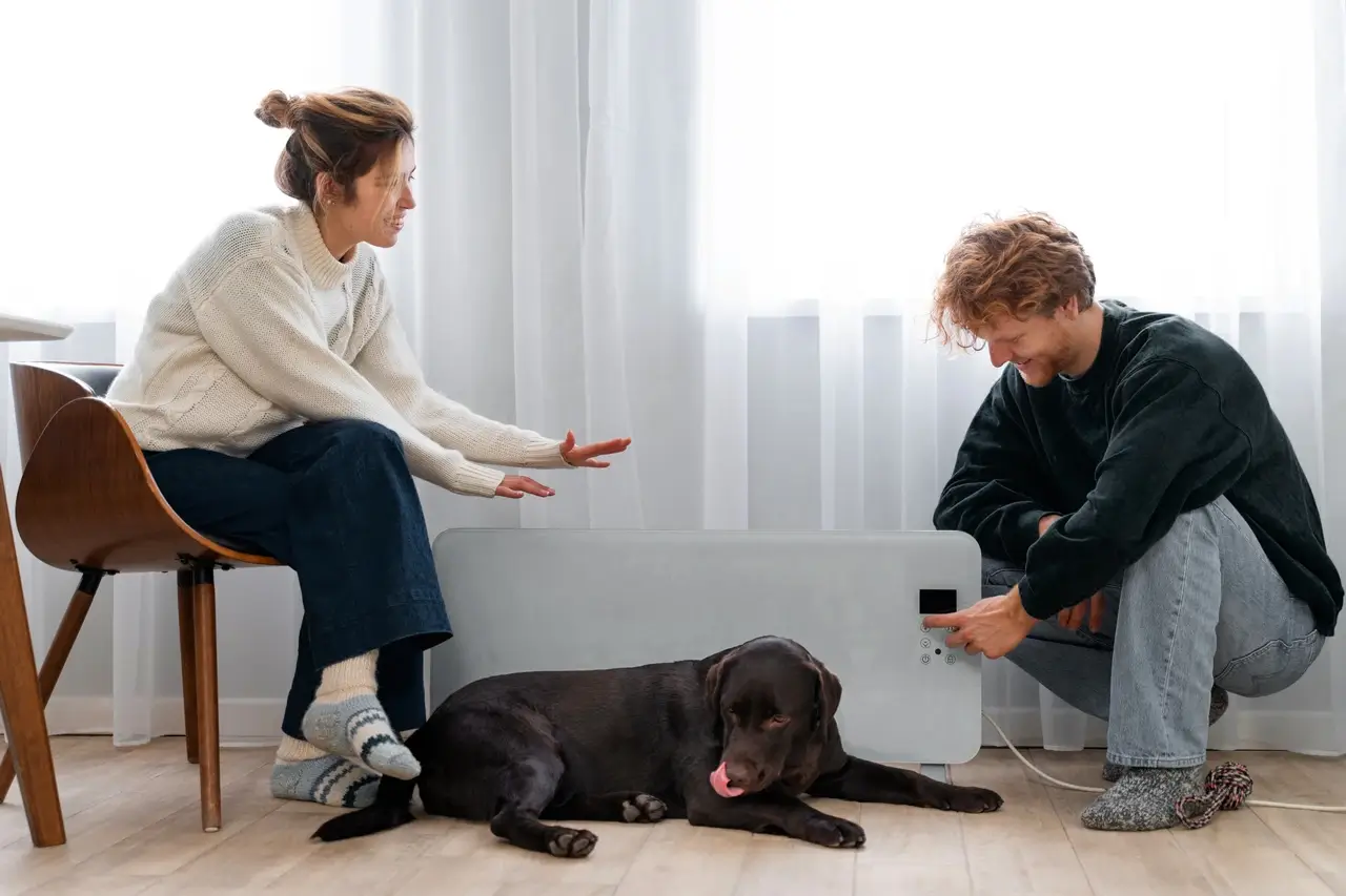 A woman and a man training a black dog indoors.